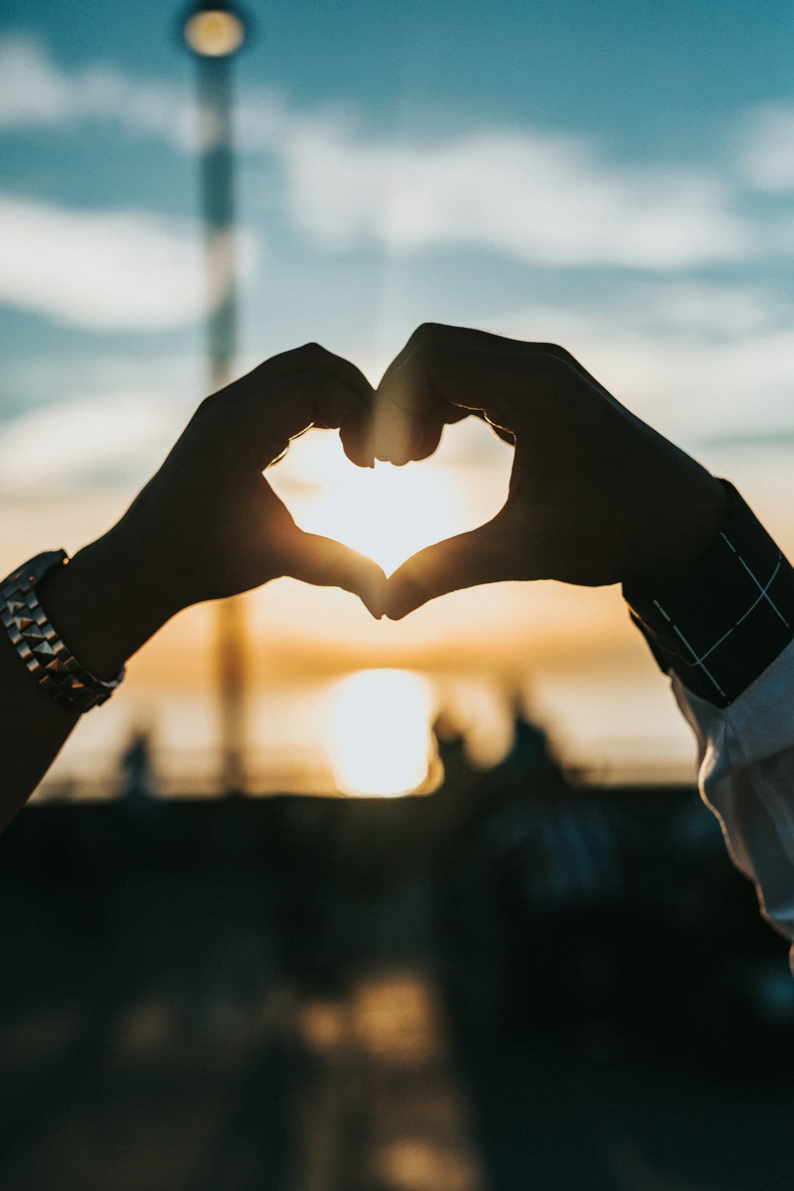 Two people forming a heart with their hands in warm evening light